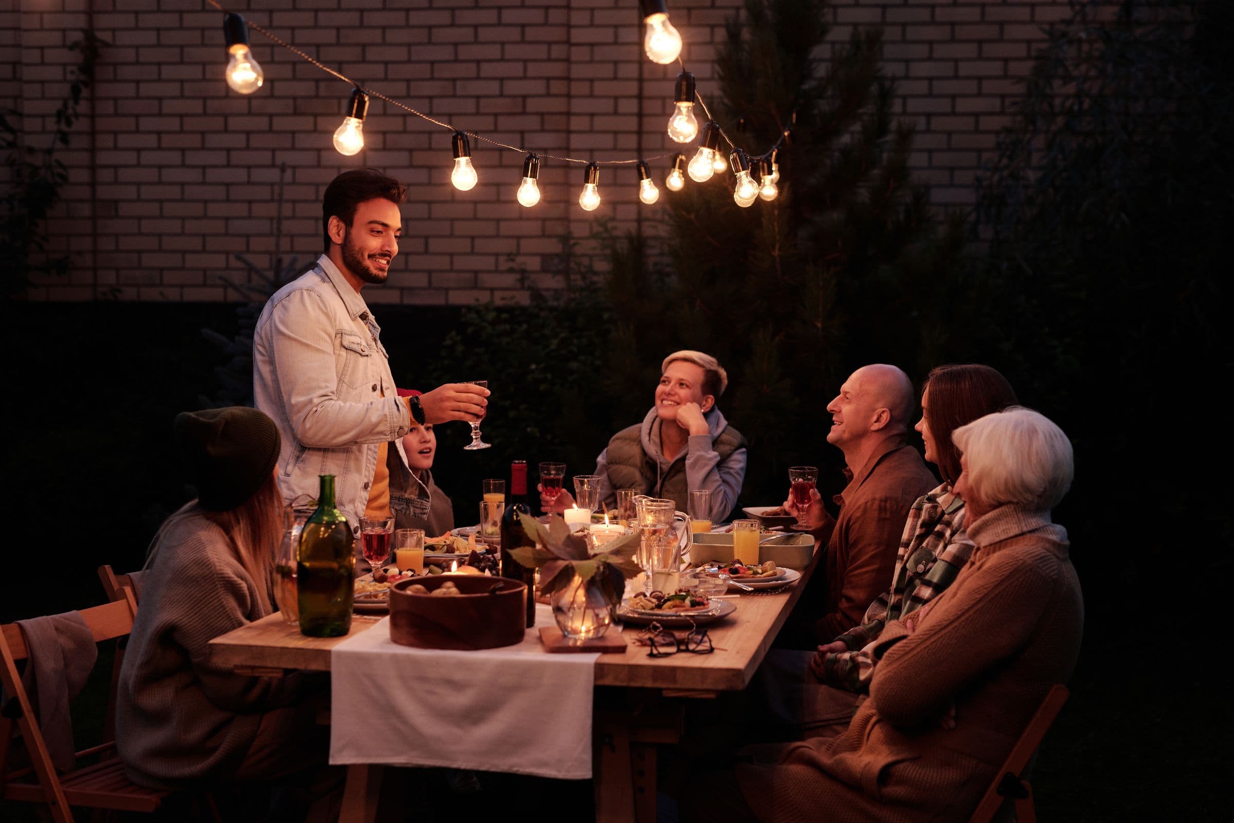 Friends raising a toast at a garden dinner under string lights